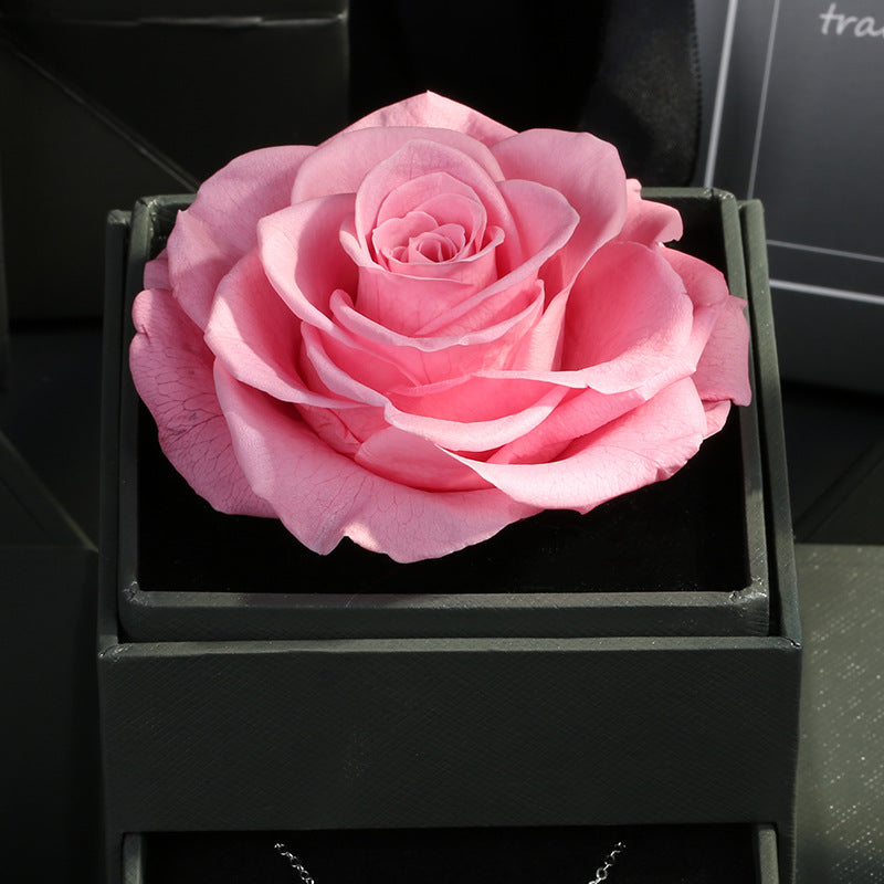 Pink preserved rose in clear acrylic box above gray pull-out jewelry drawer, romantic gift